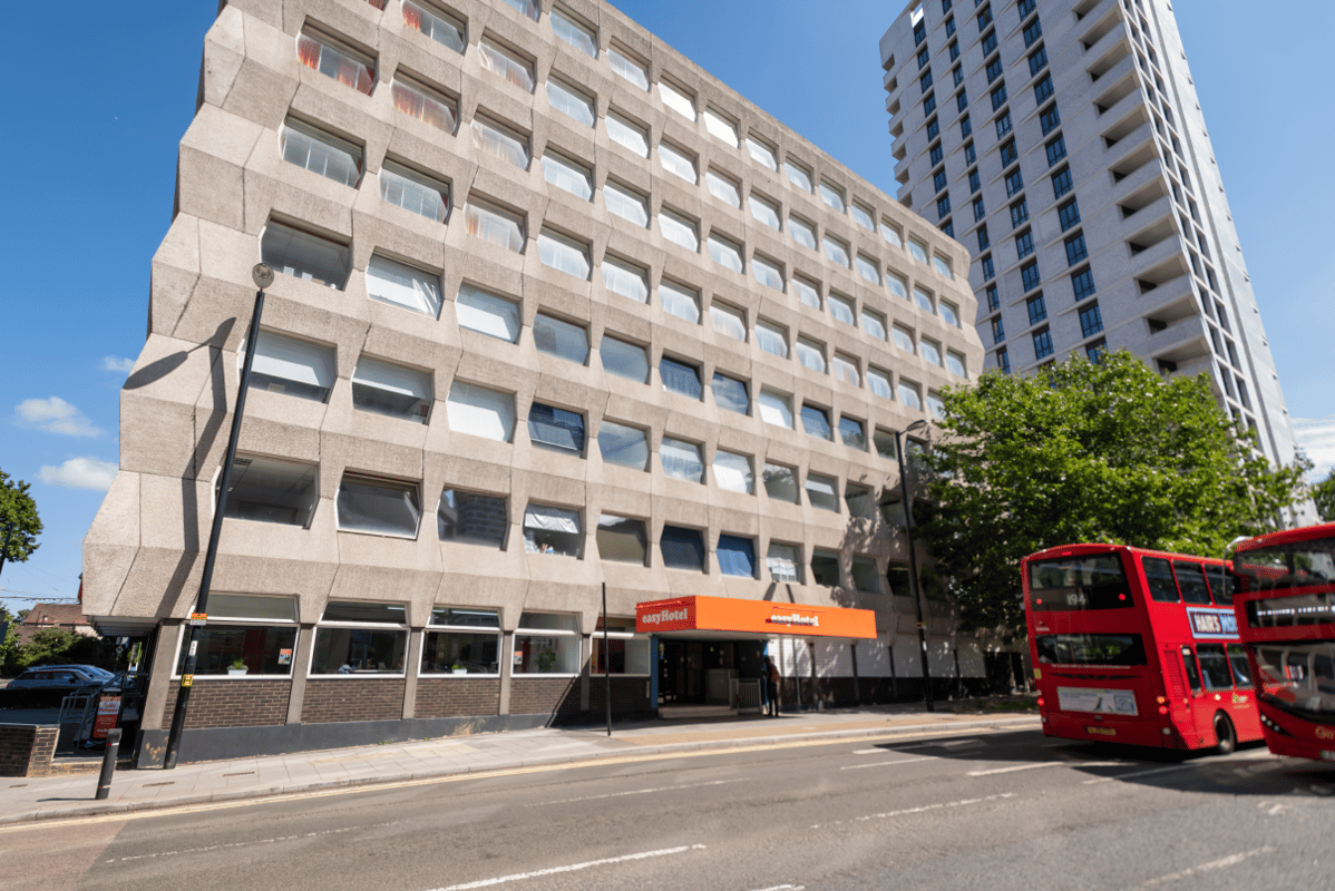 Exterior street view of easyHotel Croydon building with red double-decker buses.