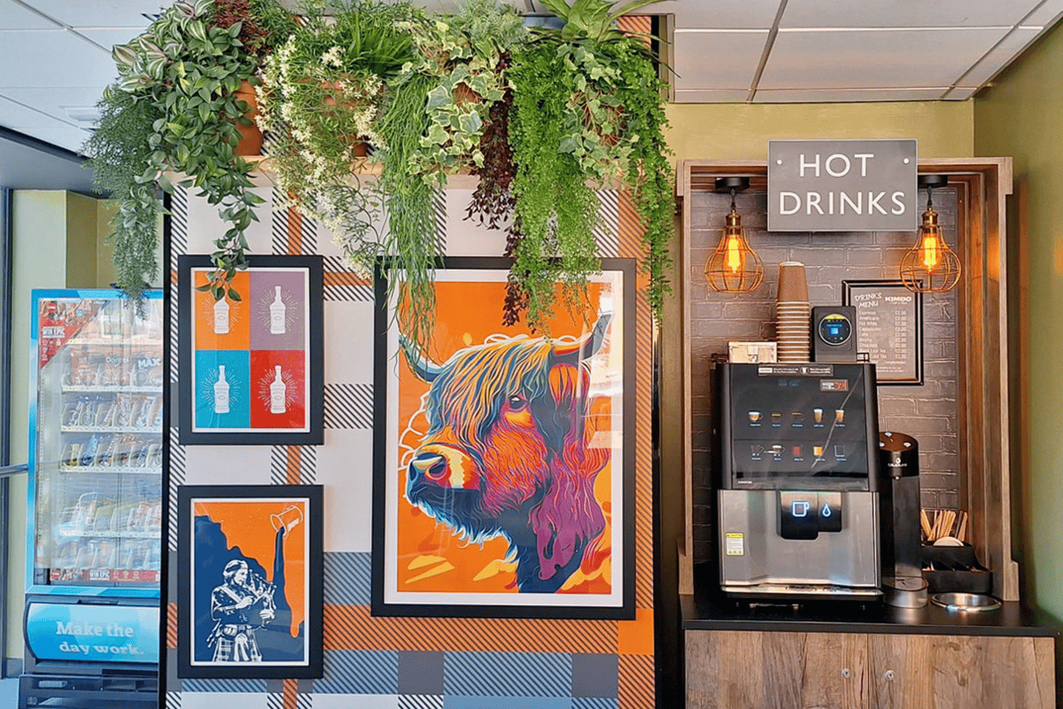 Vibrant common area at easyHotel Glasgow featuring Scottish-themed pop art, including a prominent colorful Highland Cow print, a self-service hot drinks station, and a vending machine.