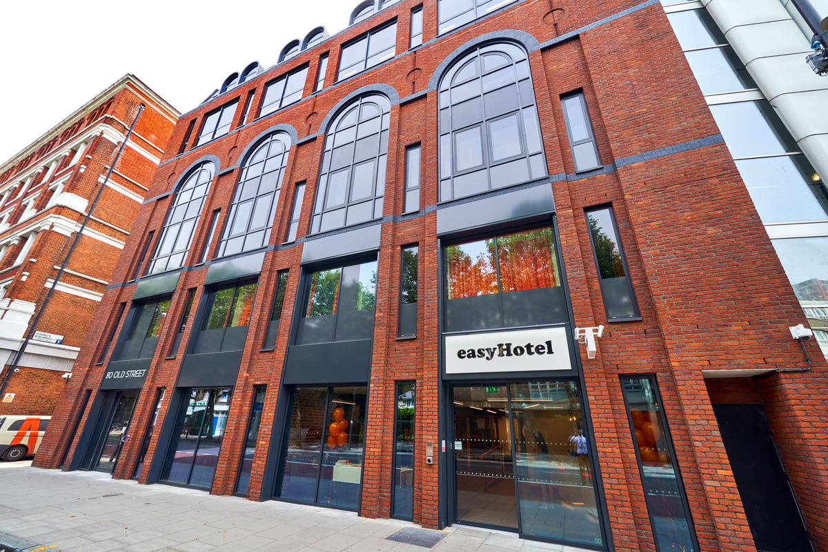 Exterior view of easyHotel London Old Street, a modern red brick building with large arched windows and a prominent easyHotel sign at the entrance.