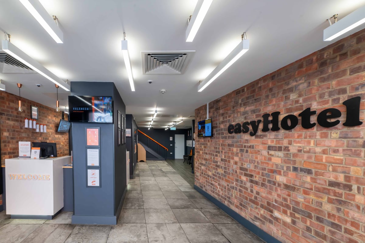 easyHotel Leeds City Centre reception area with brick wall and illuminated signage.
