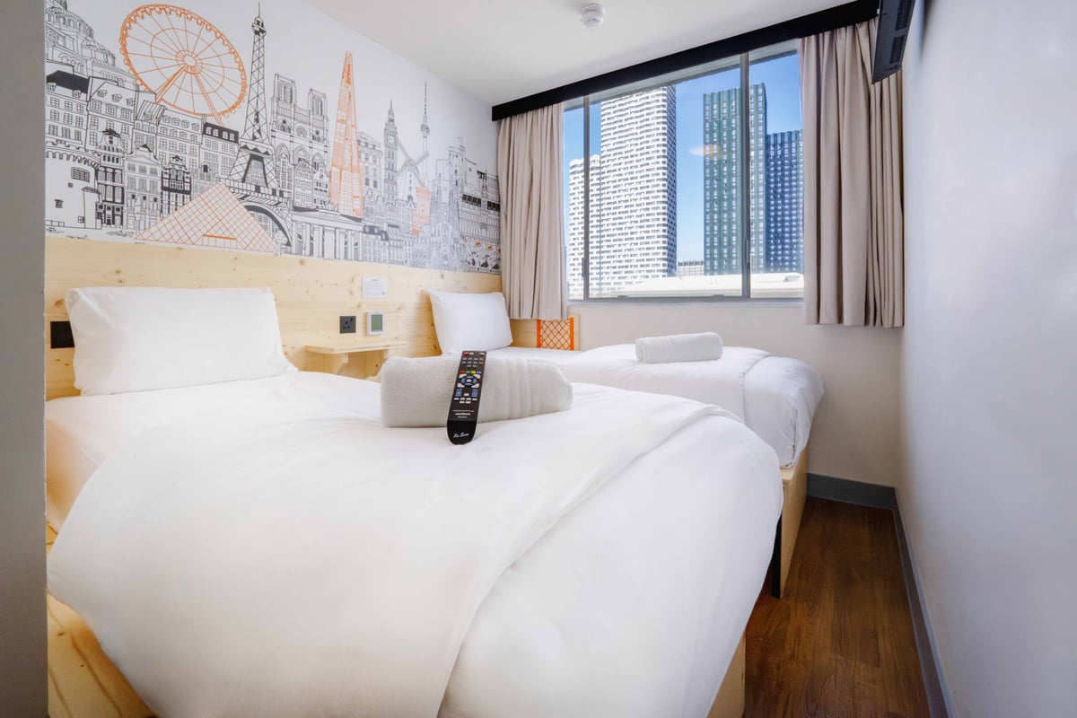 EasyHotel London Croydon twin room with two single beds, white linens, and a cityscape mural.