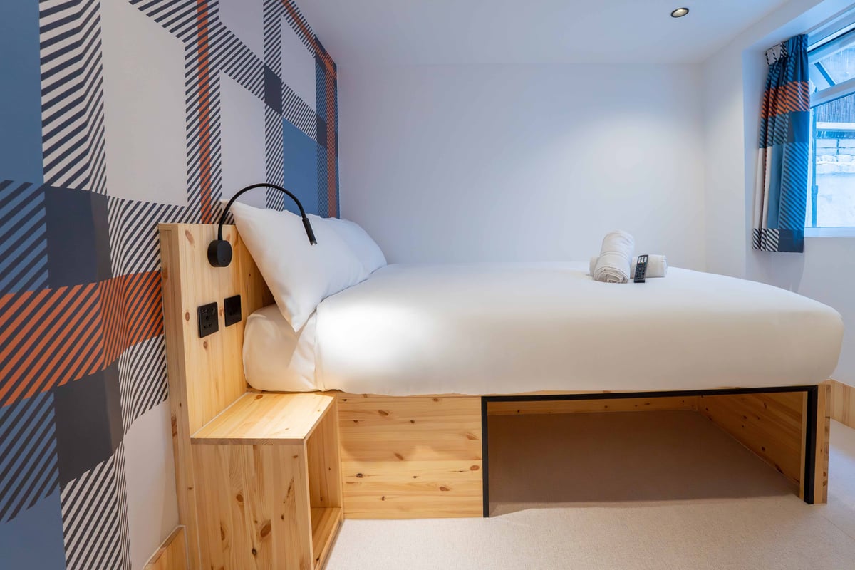 EasyHotel Paddington accessible double room with a double bed, white linens, and a patterned accent wall.