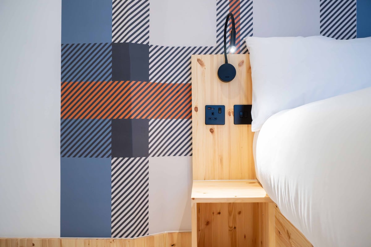 EasyHotel Paddington accessible double room with a bed, bedside table, and electrical outlets.