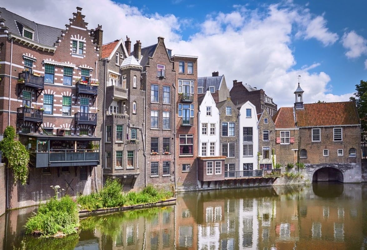 Scenic view of traditional Dutch canal houses along the Oude Haven in Rotterdam, Netherlands, reflecting in the calm water under a blue sky.
