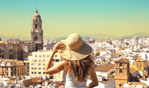 Woman wearing a straw hat overlooks the cityscape of Seville, Spain, featuring the Giralda tower.